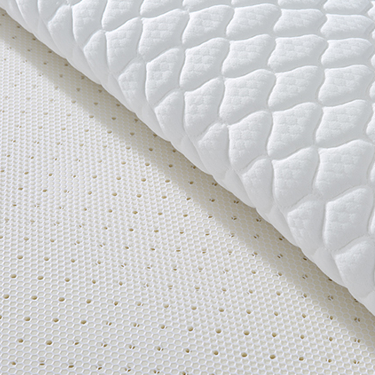 Detail shot of the white quilted mattress surface and perforated latex layer