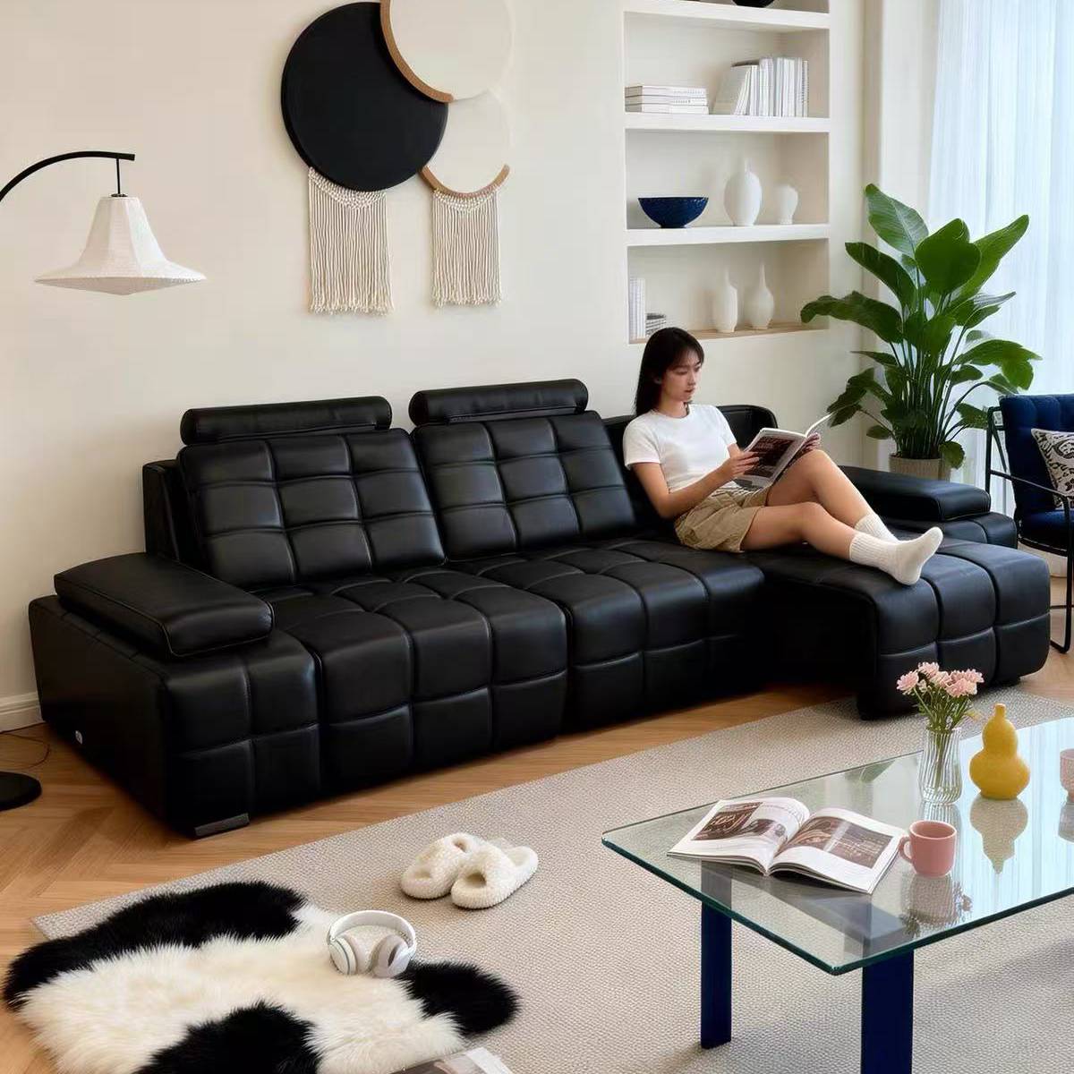 Side view of the black electric sofa bed with a woman reading a magazine