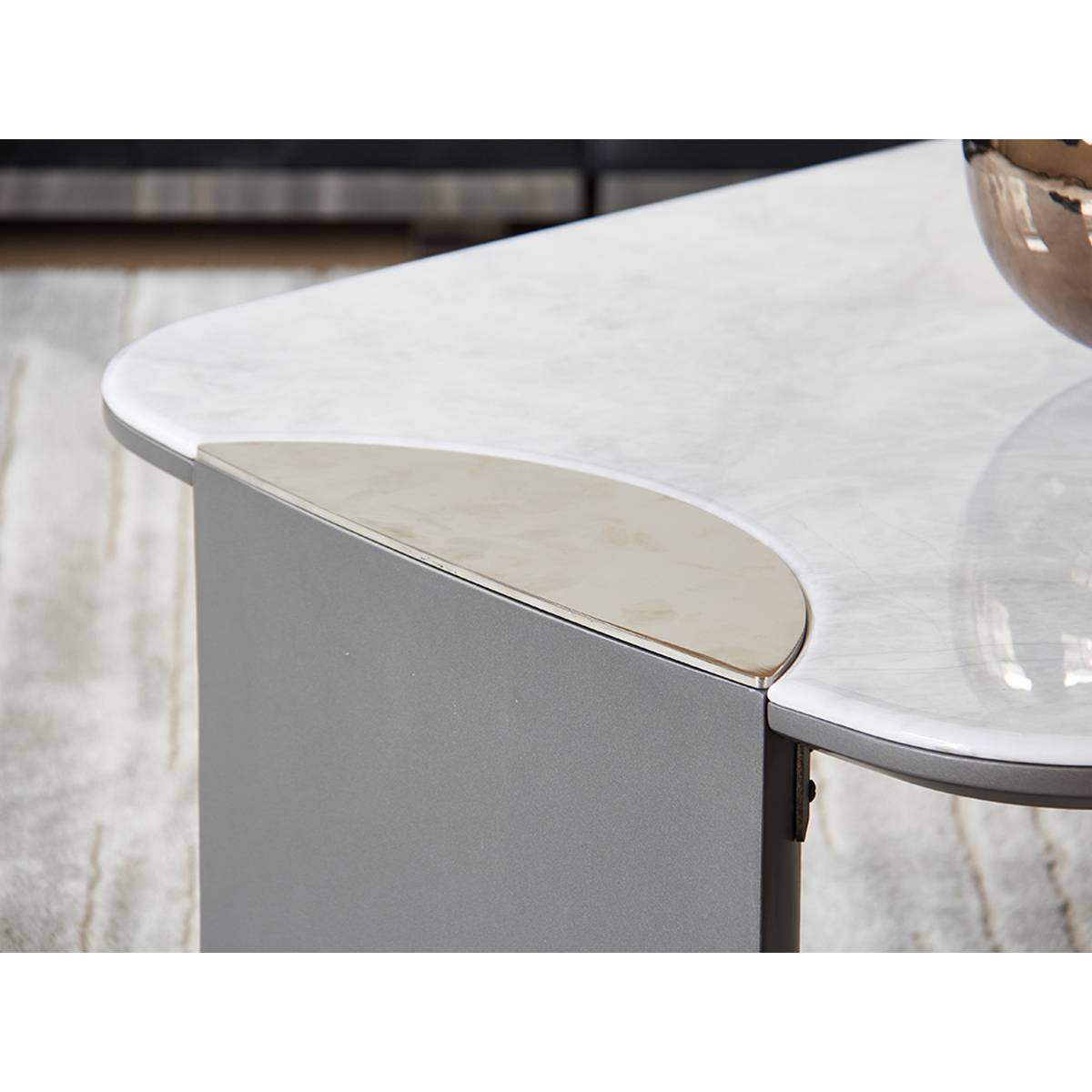 Close-up detail of the coffee table corner showing the curved microcrystalline stone top and stainless steel trim