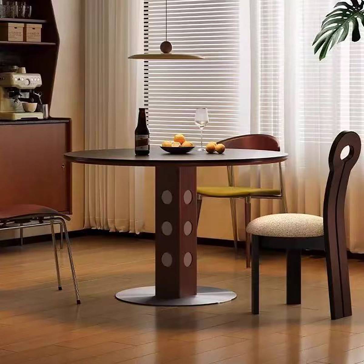 Side view of the dark wood round dining table with a bottle and fruit bowl