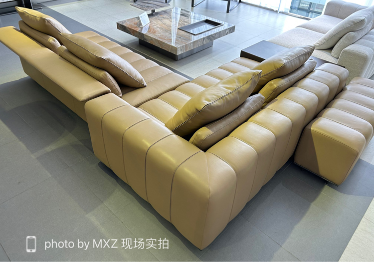 Wide angle view of the beige leather sofa in a showroom setting