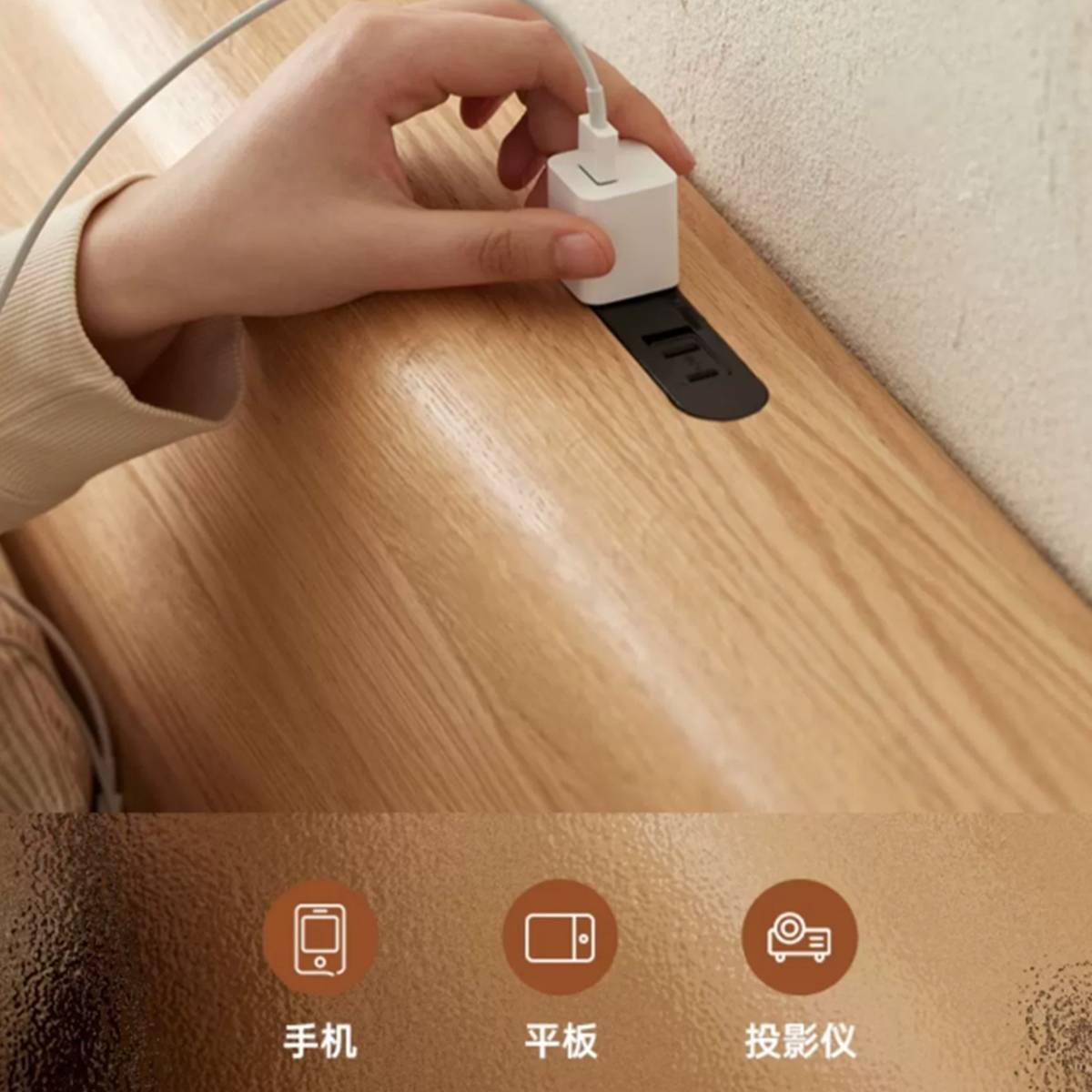 Close-up of the headboard shelf showing a hand plugging a charger into the built-in power outlet.