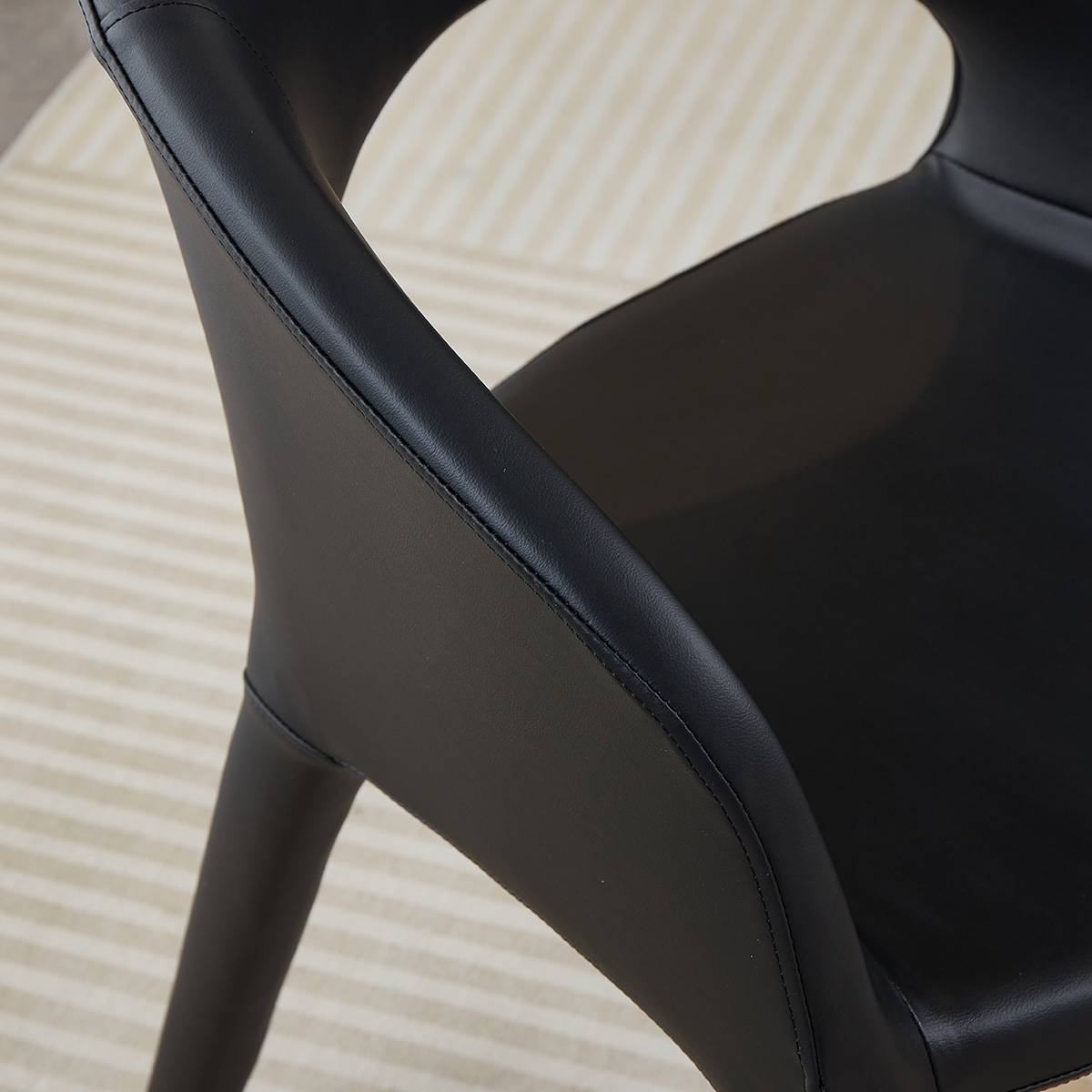 Close-up detail of the black microfiber leather upholstery and stitching on the chair's armrest.