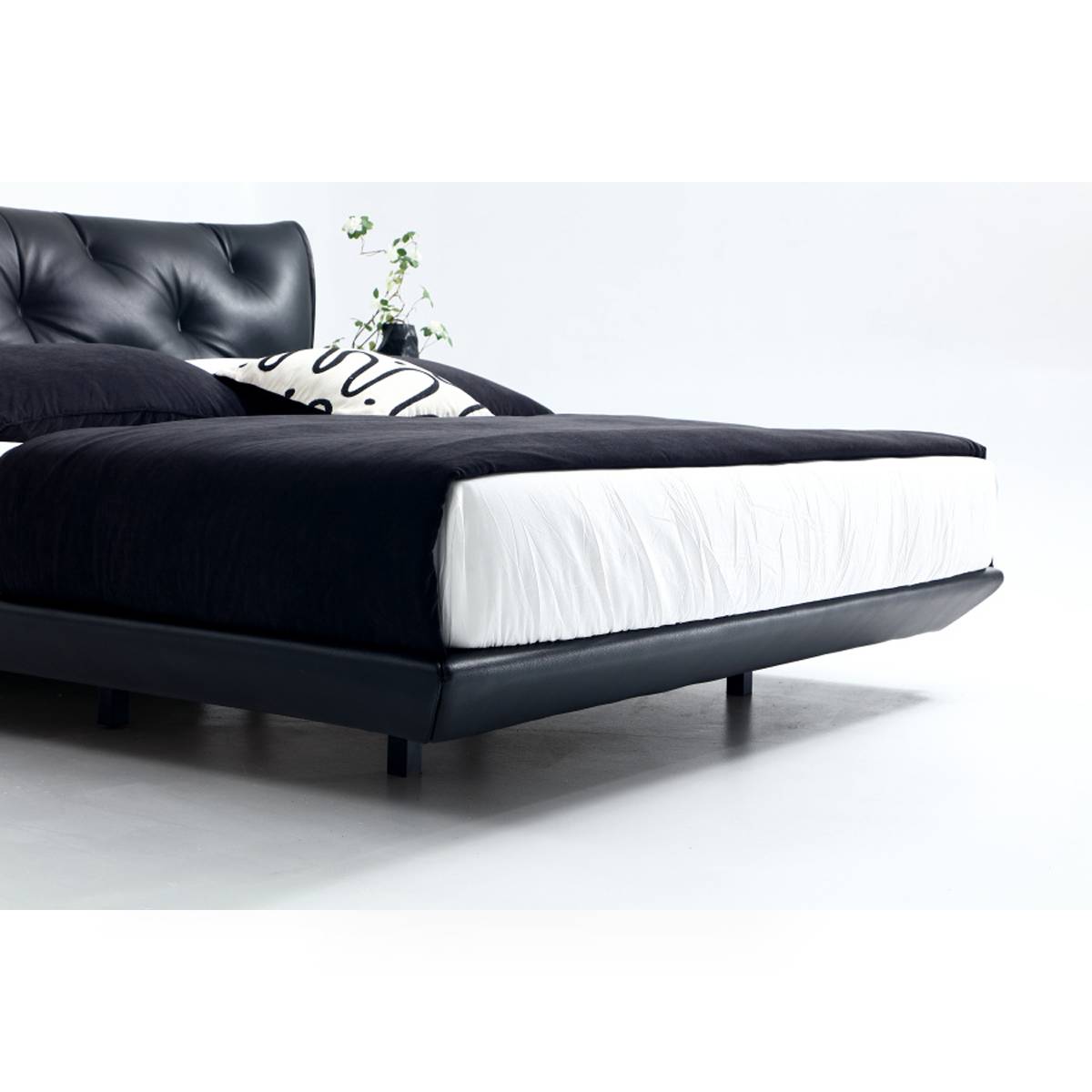 Side view of the black leather tufted bed showing the frame and mattress