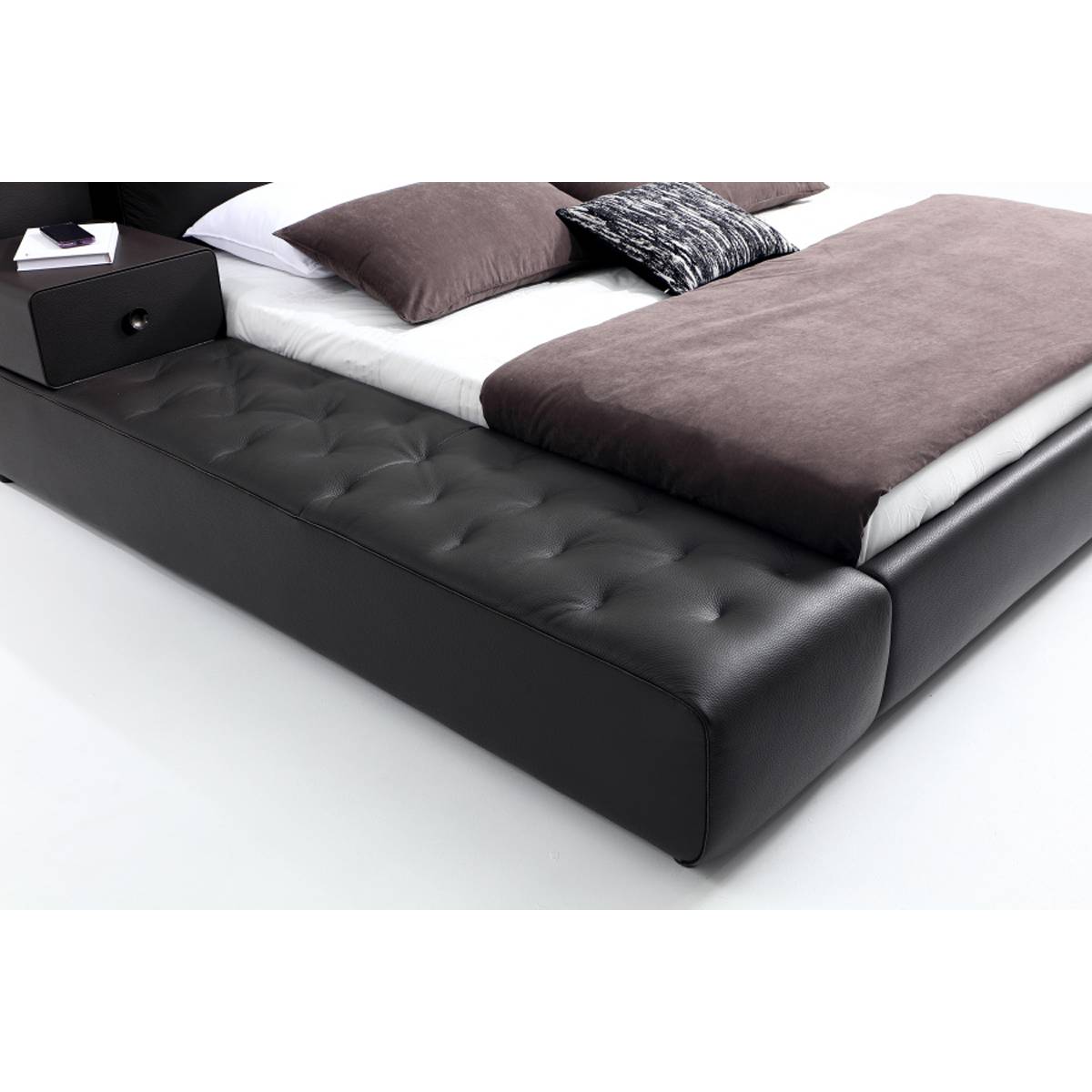 Side view of the bed showing the tufted leather base and brown bedding