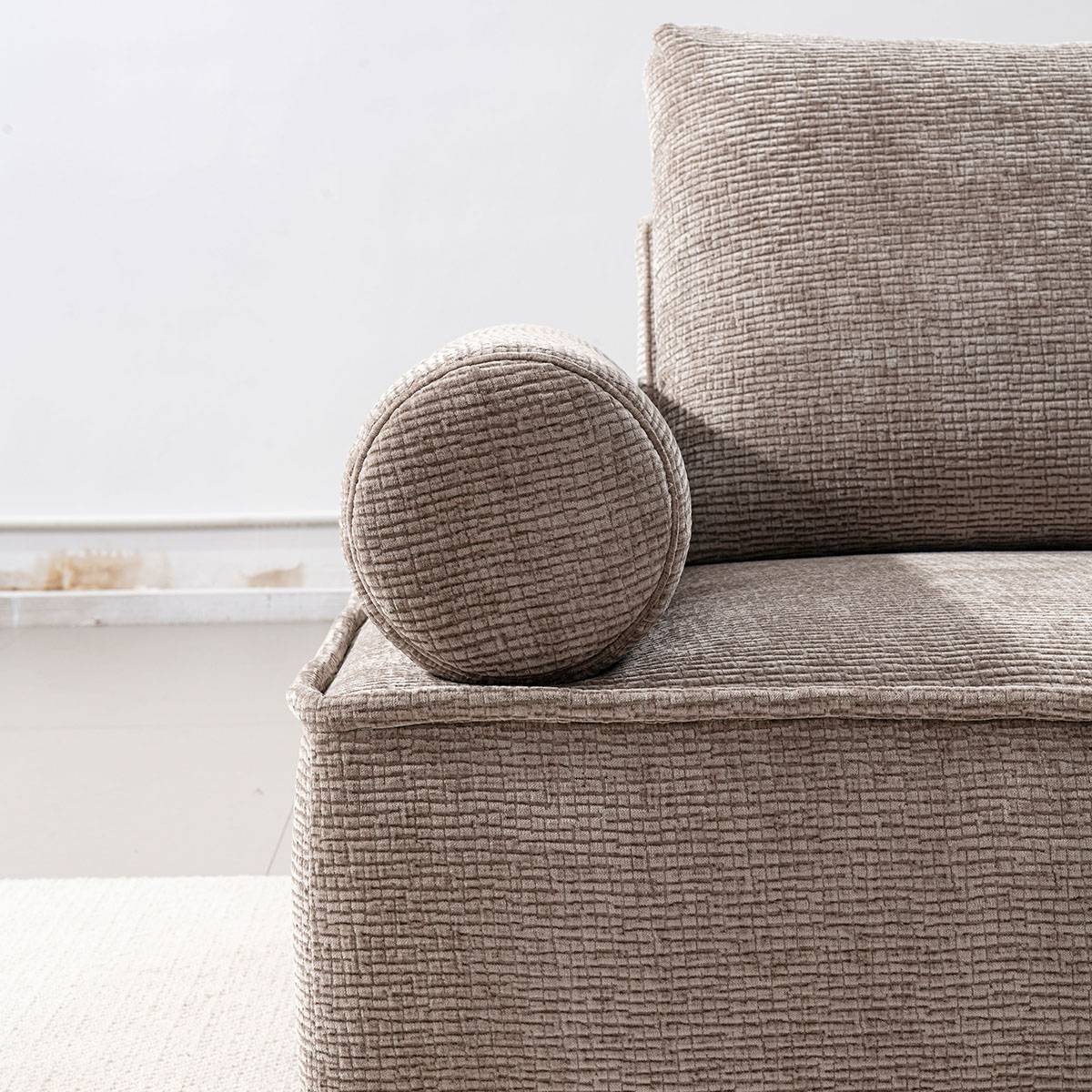 Close-up of the sofa's cylindrical armrest and textured fabric