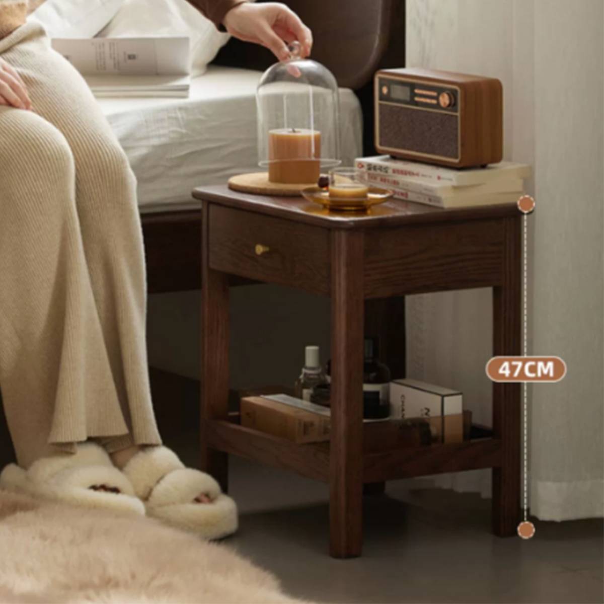 Bedside table placed next to a bed with a person sitting, showing scale and usage context.
