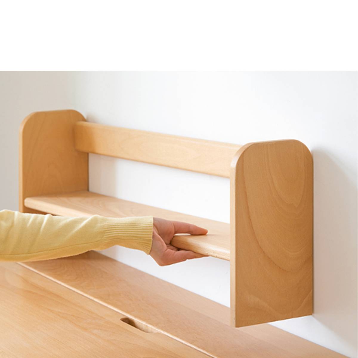 Close-up of a hand adjusting the height of the integrated wooden shelf on the desk.