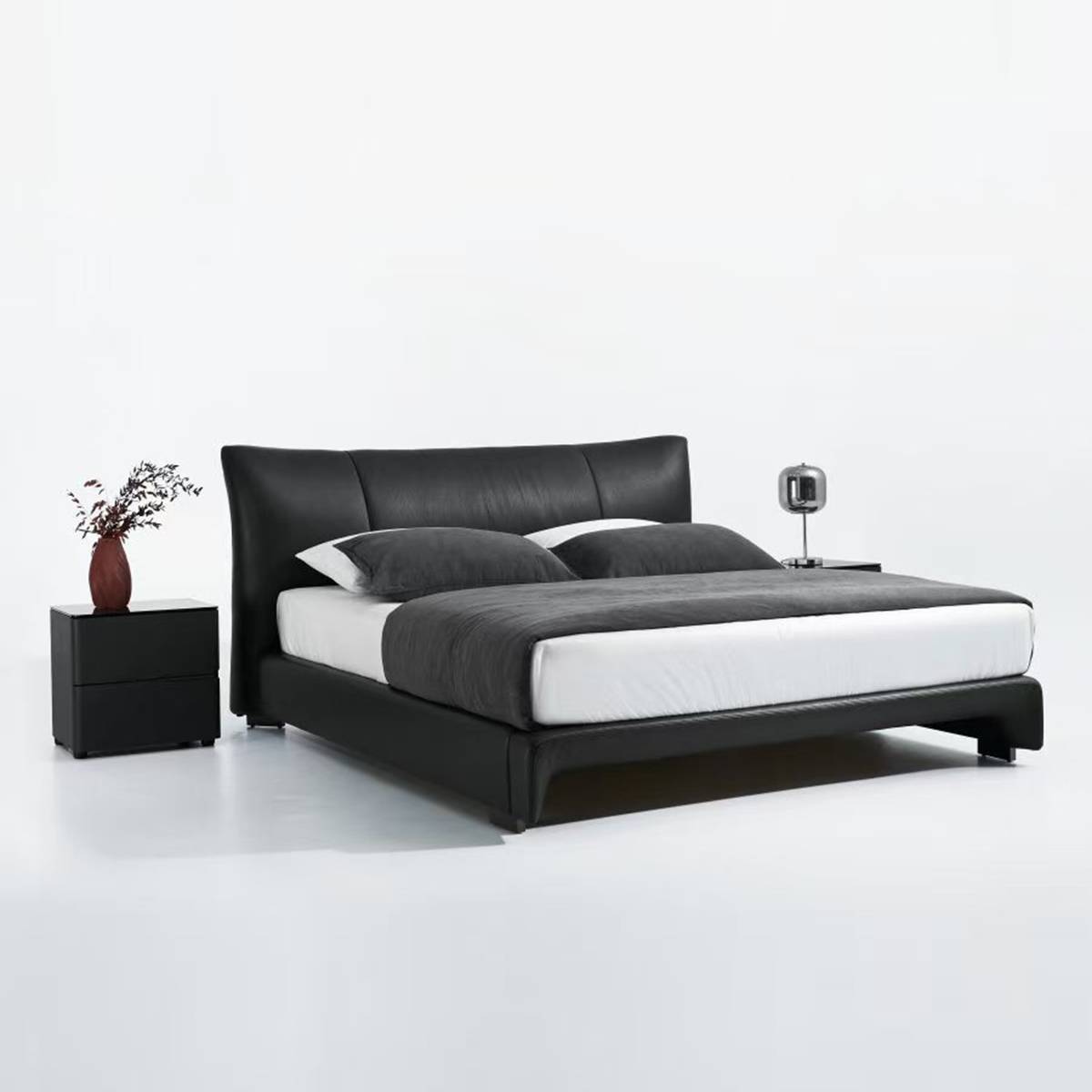 Side angle view of the black leather bed with bedside tables.