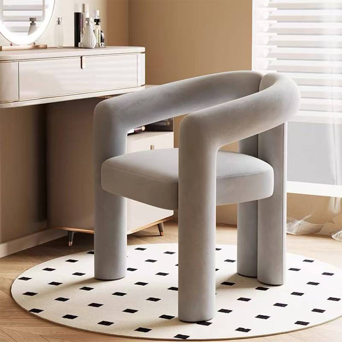 Grey lounge chair with curved frame placed in front of a vanity desk