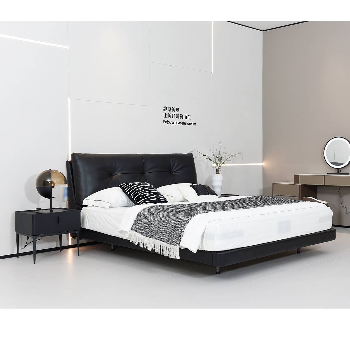 Side view of the black leather bed with white bedding and bedside table