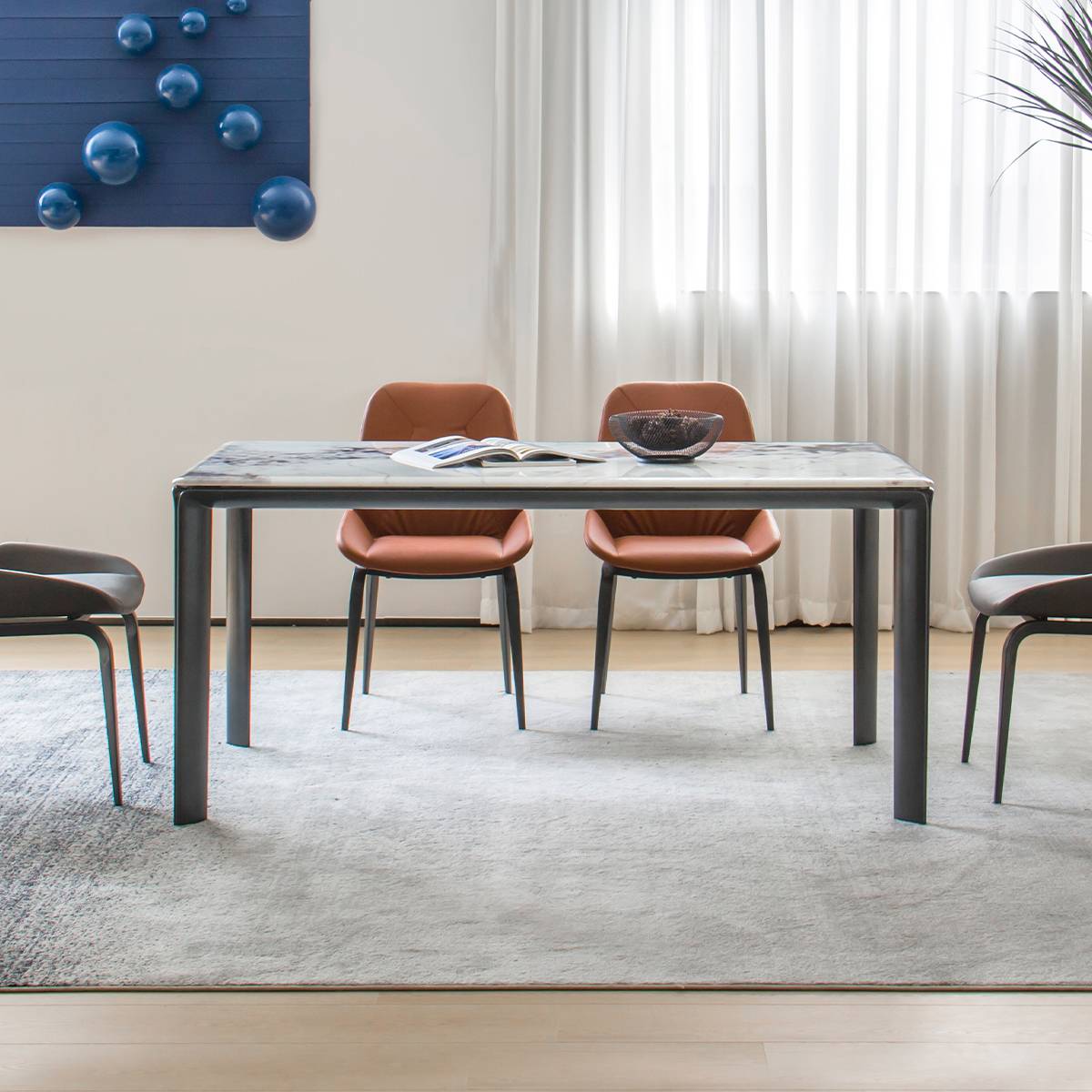 Front view of the dining table with brown chairs and a blue wall art piece in the background