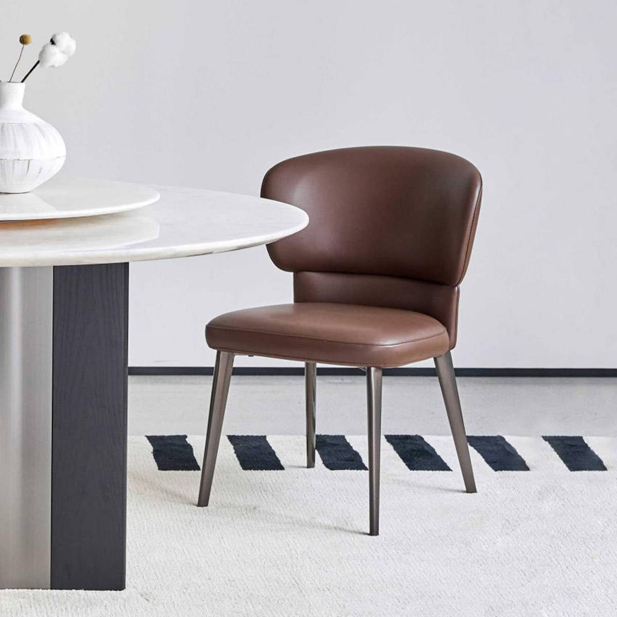 Dark brown faux leather dining chair with metal legs next to a white table