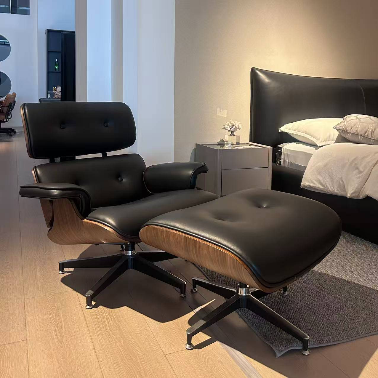 Front view of black leather Eames lounge chair and ottoman in a bedroom setting