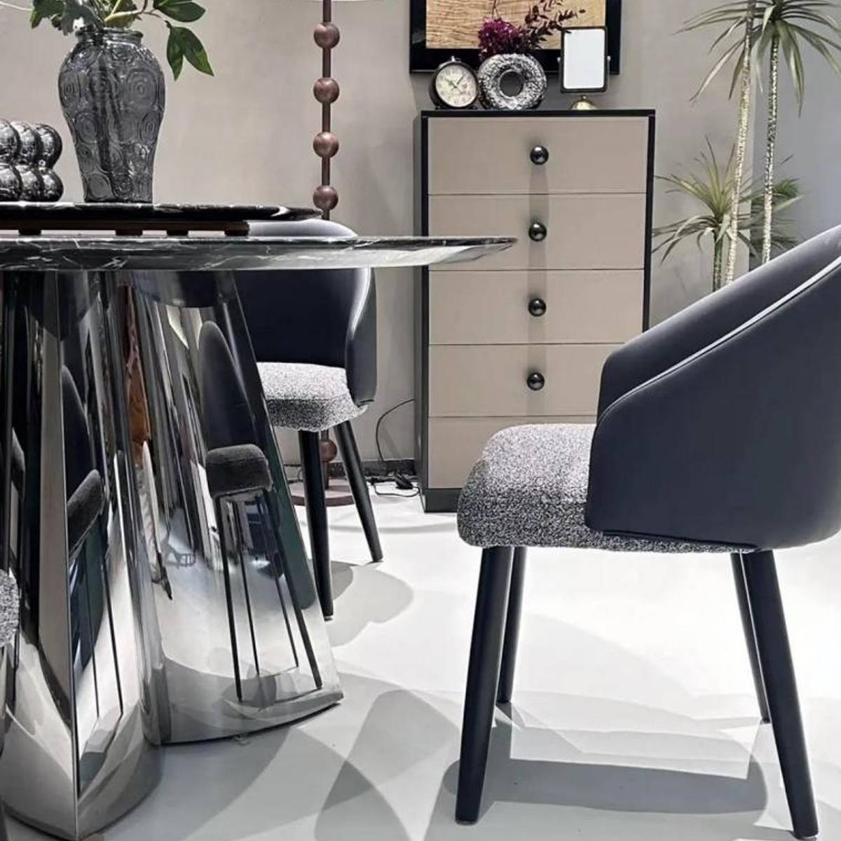 Close-up detail of the stainless steel mirror clover base and marble edge of the dining table