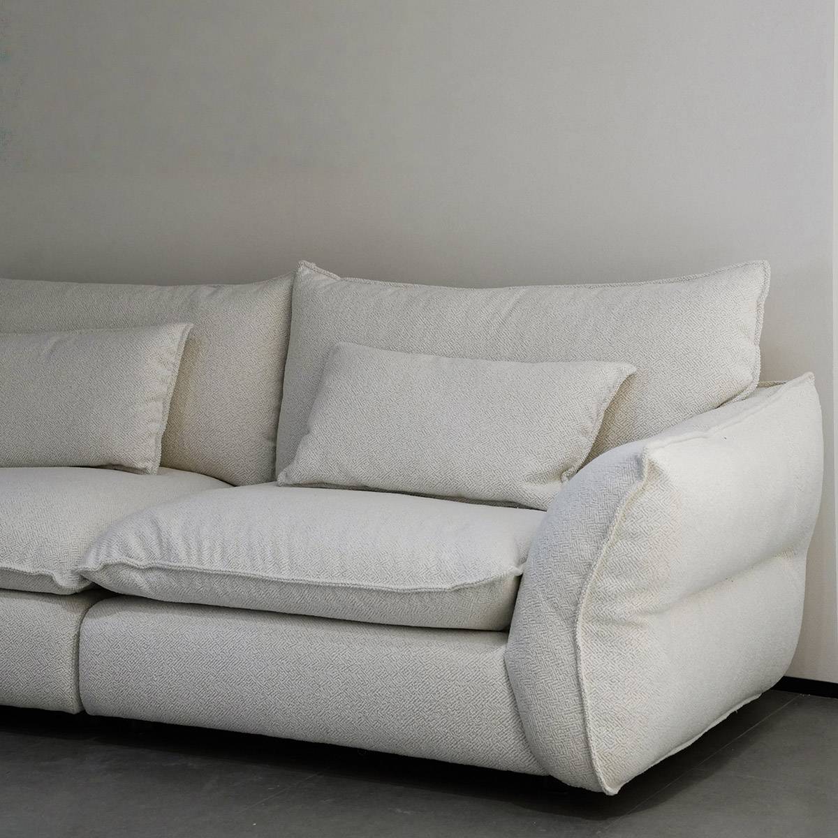 Close-up view of the cream fabric sofa showing the texture of the upholstery and the armrest design.
