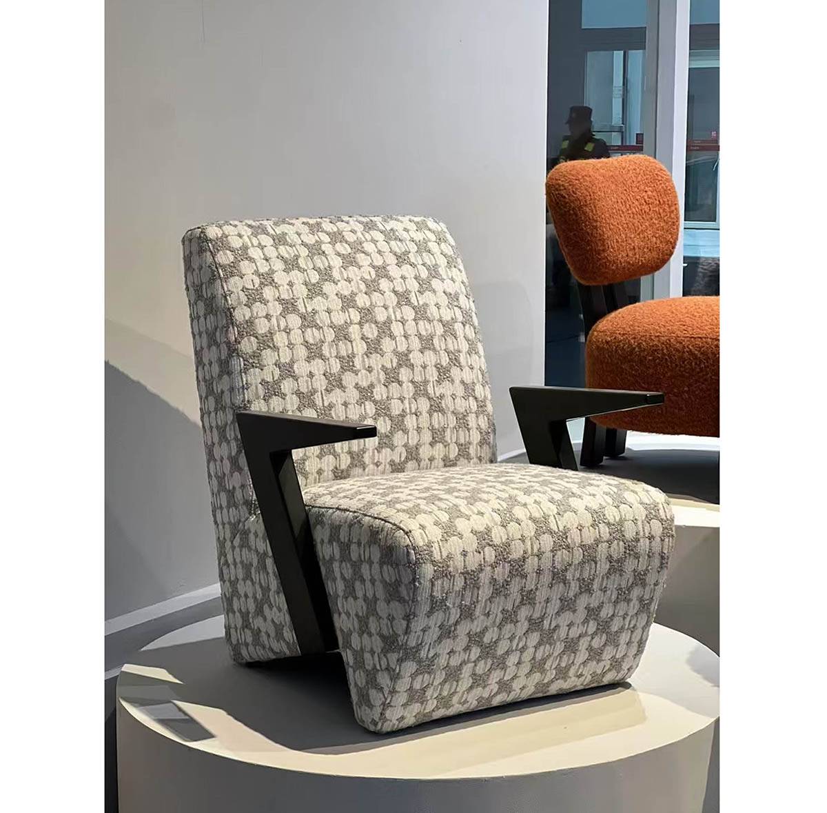 Lounge chair displayed on a white pedestal in a showroom setting