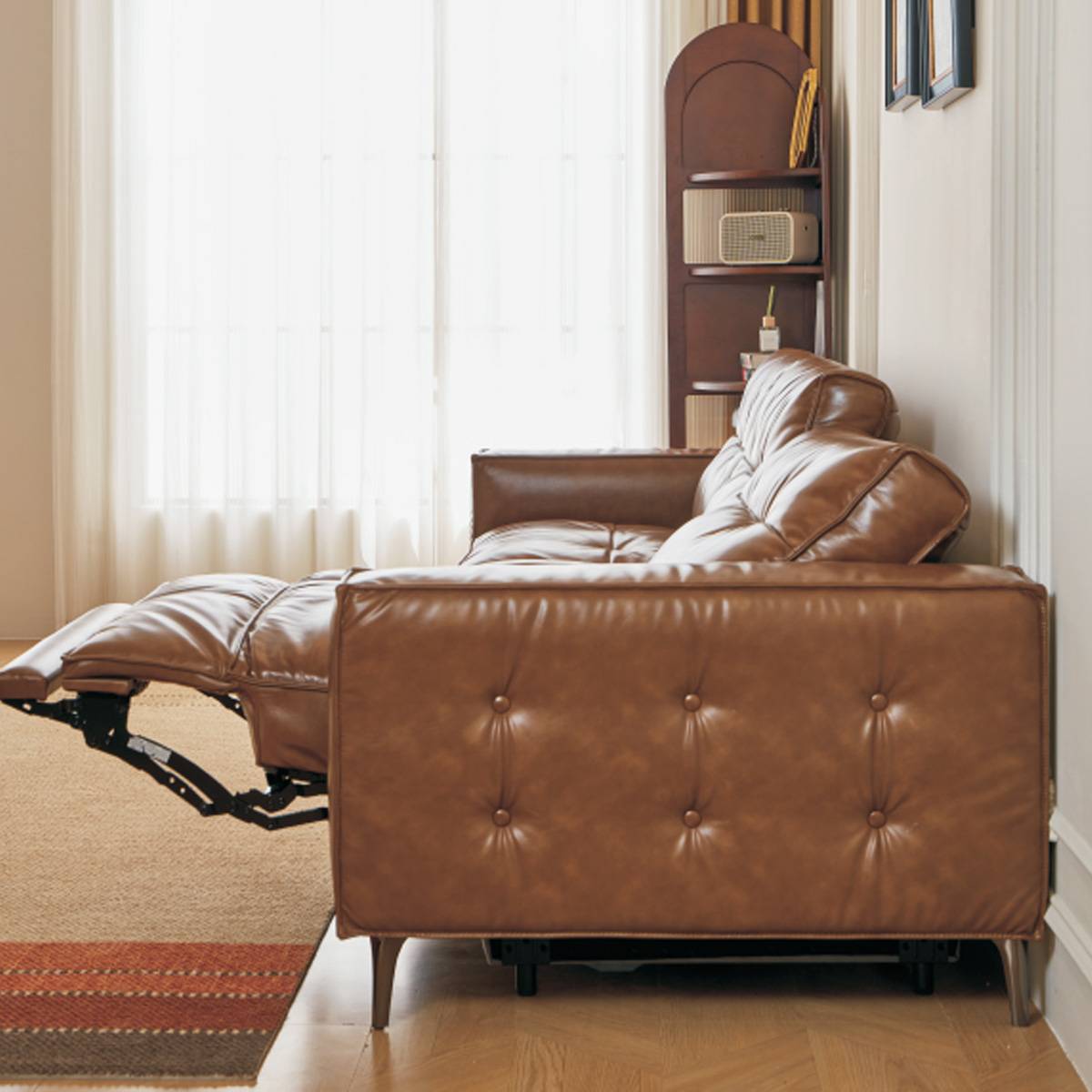 High-angle view of the brown leather sofa showing the tufted seat cushions and extended footrest.