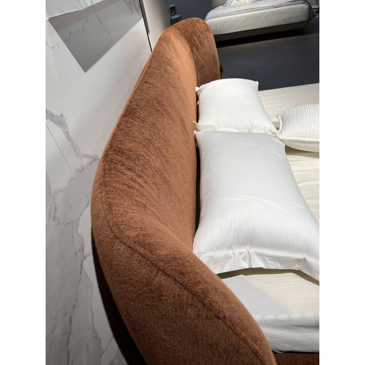 Side view of the brown chenille upholstered bed headboard with white pillows