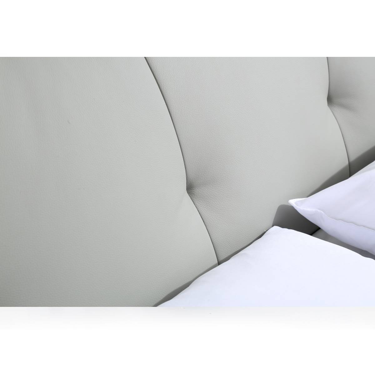 Close-up view of the grey tufted leather headboard of the soft bed