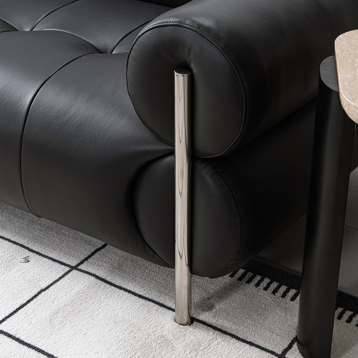Front view of black leather sofa with tufted back and chrome legs