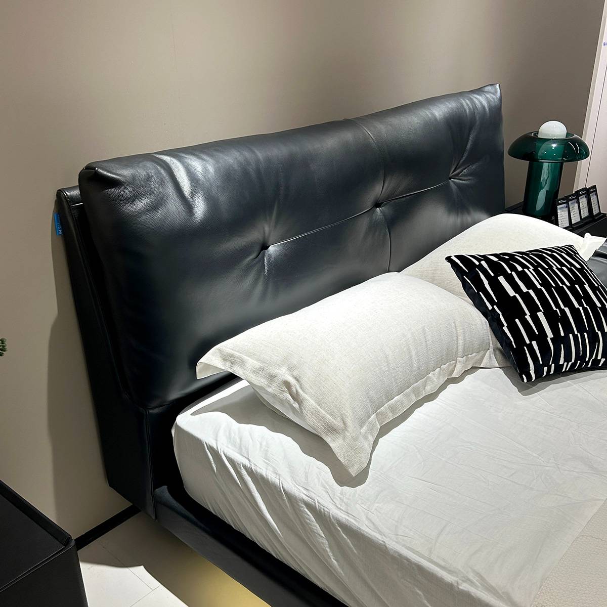 Close-up of the black leather tufted headboard and white bedding