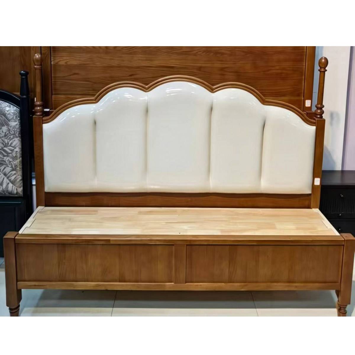 Front view of a mid-century style wooden bed with a cream leather upholstered headboard and cherry wood finish.