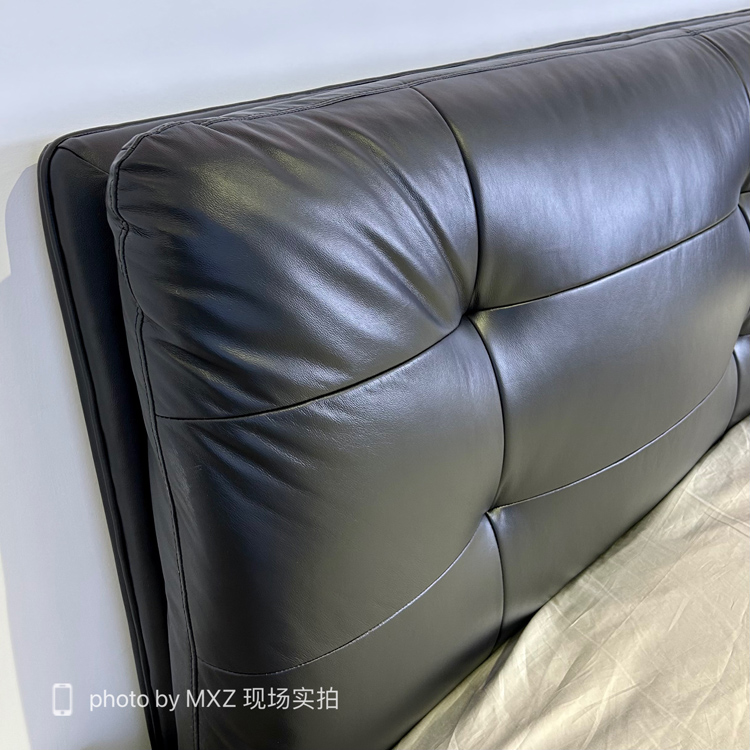 Close-up of the black leather tufted headboard showing texture and stitching