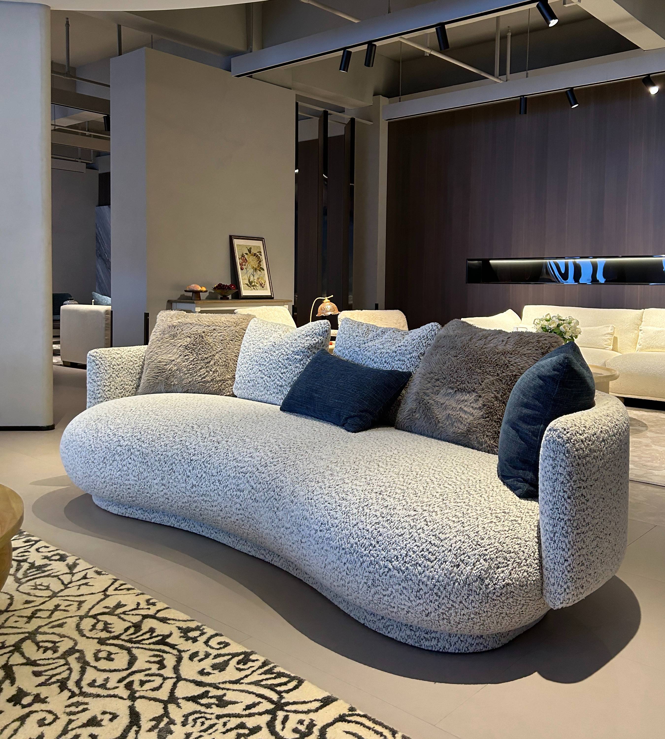 The curved sofa displayed in a showroom environment with track lighting.