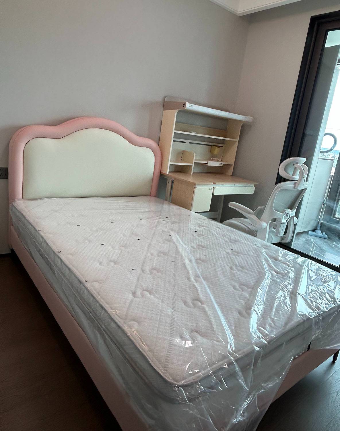 Pink upholstered bed with cloud-shaped headboard in a bedroom setting
