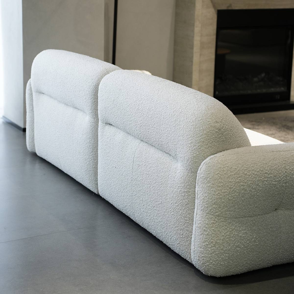Side profile view of the white fabric sofa showing the curved backrest and tufted design.