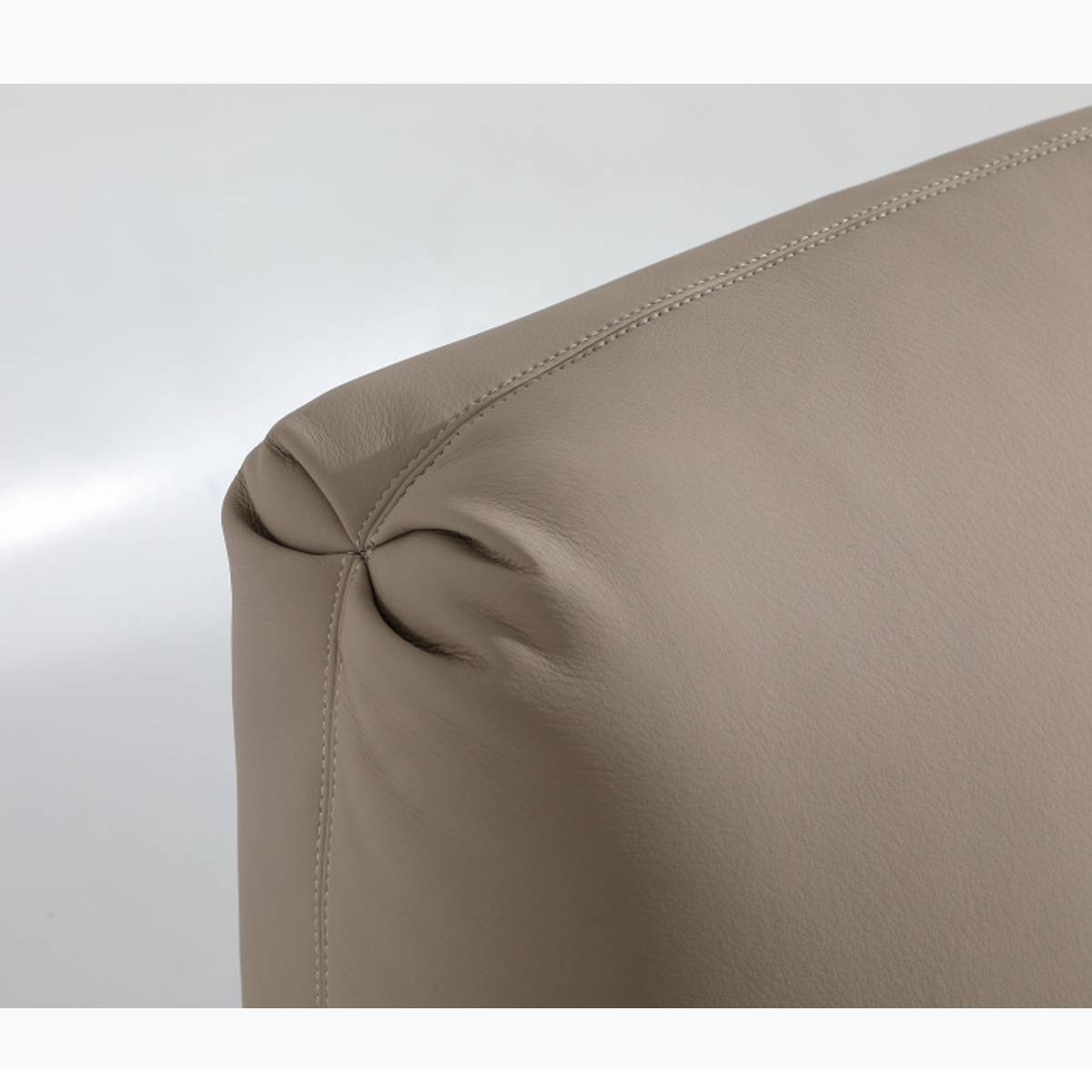 Close-up detail of the beige leather headboard showing stitching and texture