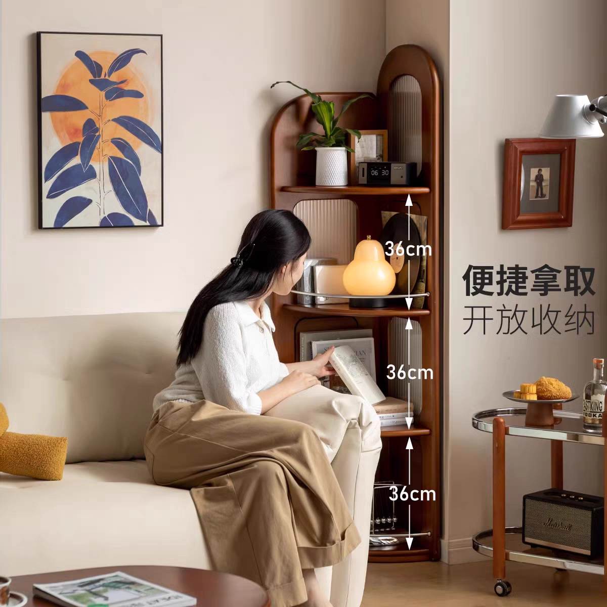 Model sitting on a sofa next to the sideboard, showing the open shelving and 36cm shelf spacing.