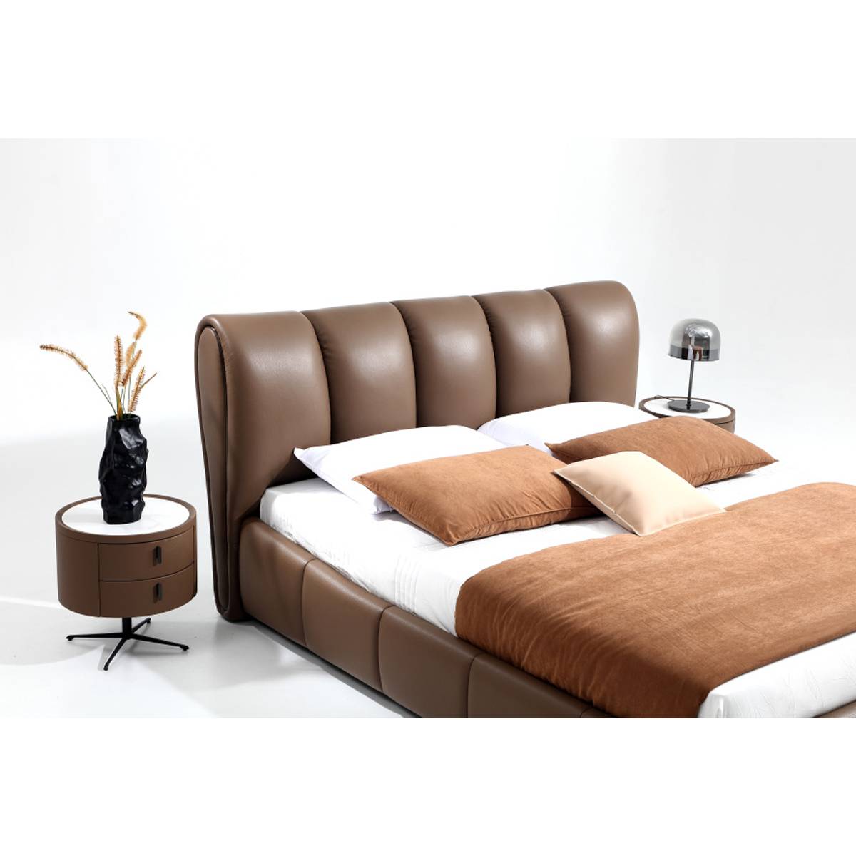 Full view of the brown leather bed with a tufted headboard, styled with pillows and a matching bedside table.