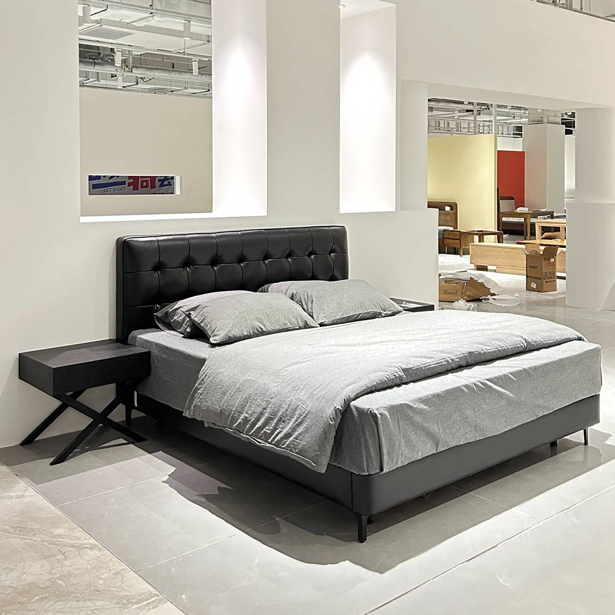 Full view of the black Barcelona bed with grey bedding in a showroom setting