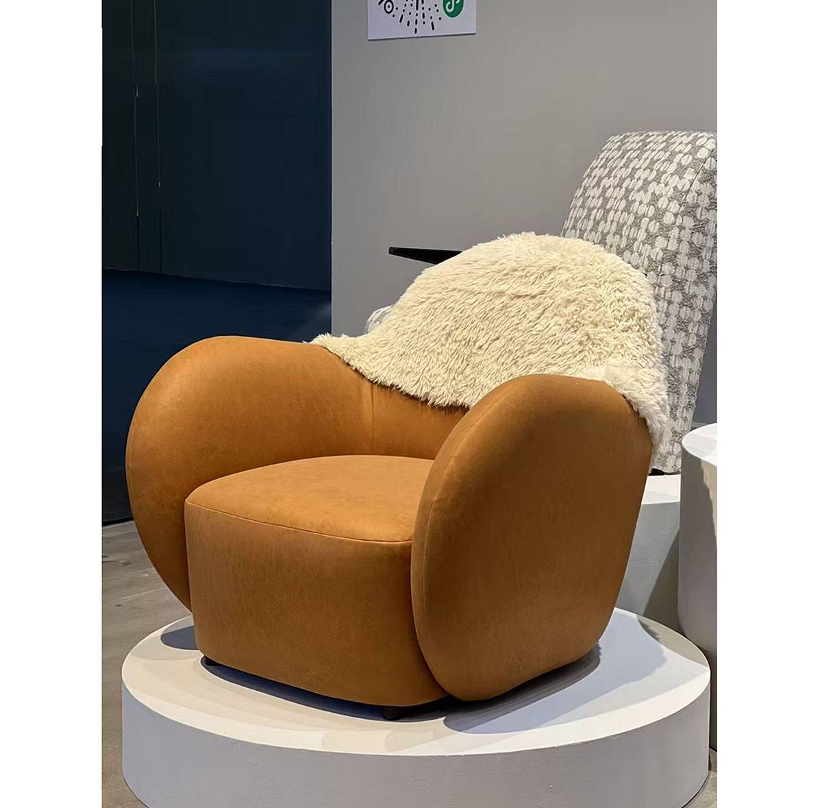 Side view of the orange lounge chair with cream fur backrest in a showroom setting