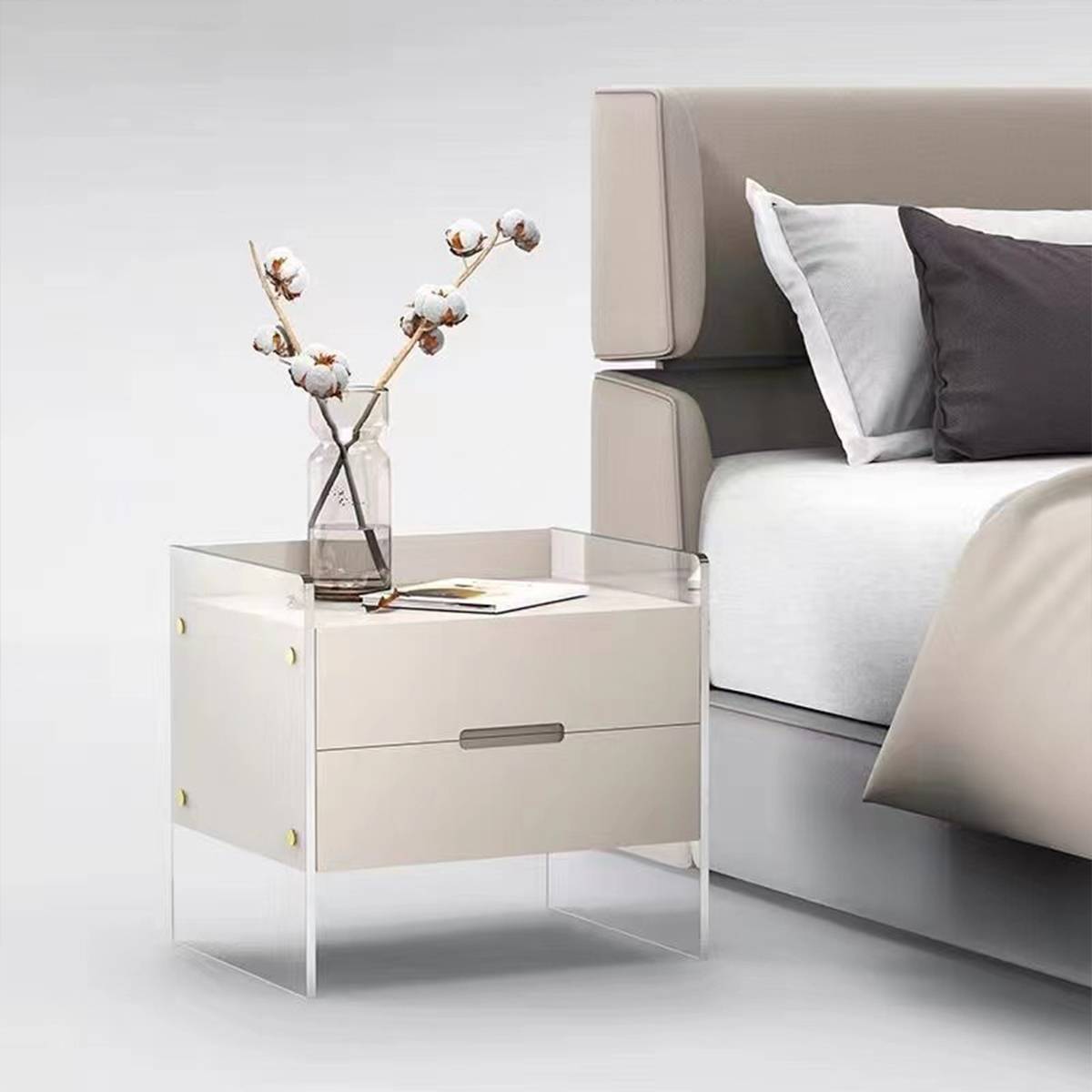 Bedside table placed next to a bed with a vase of cotton branches on top