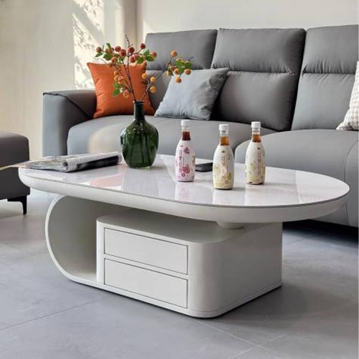 White oval coffee table with white base and drawers in a living room setting