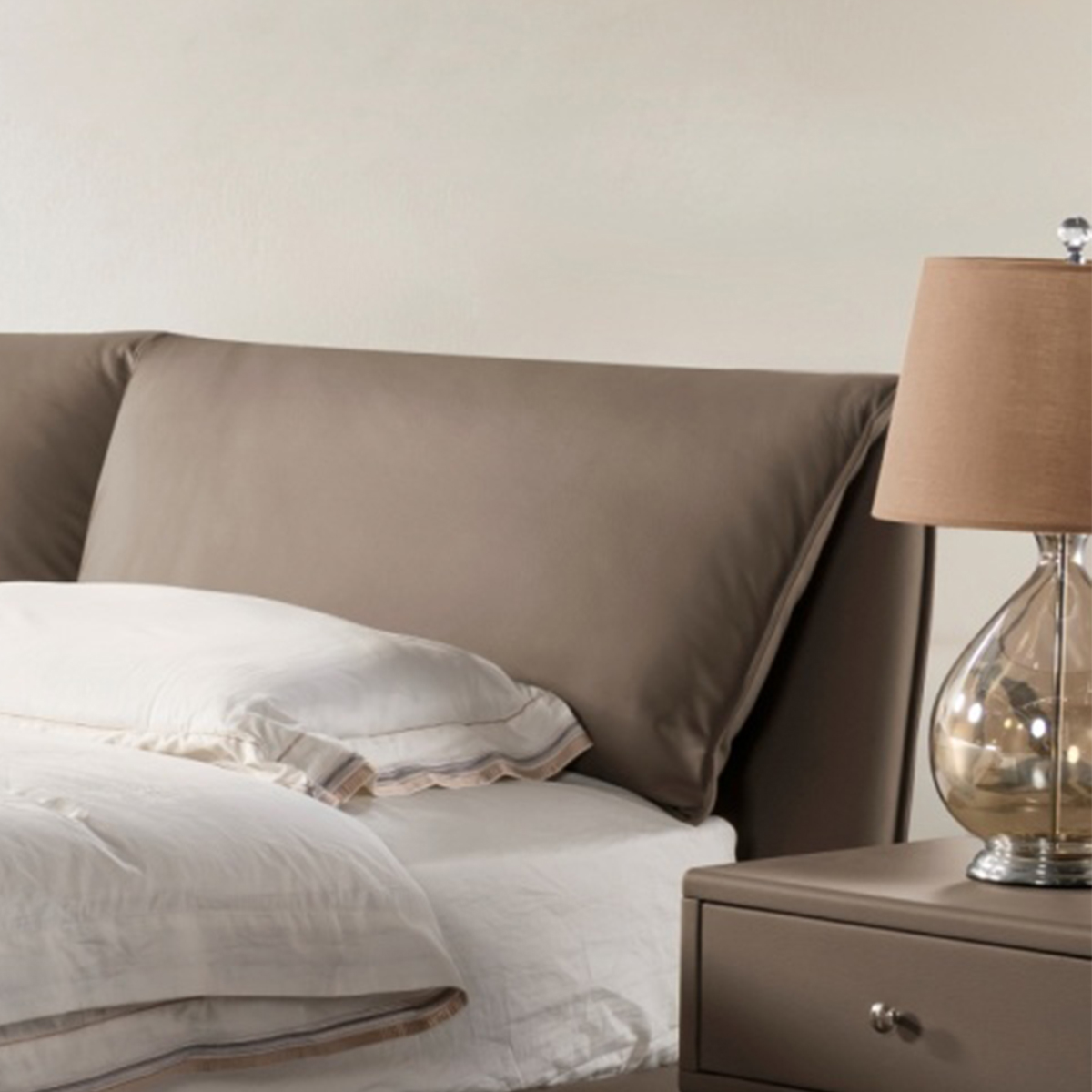 Close-up detail of the bed headboard and pillow, highlighting the leather texture and stitching.