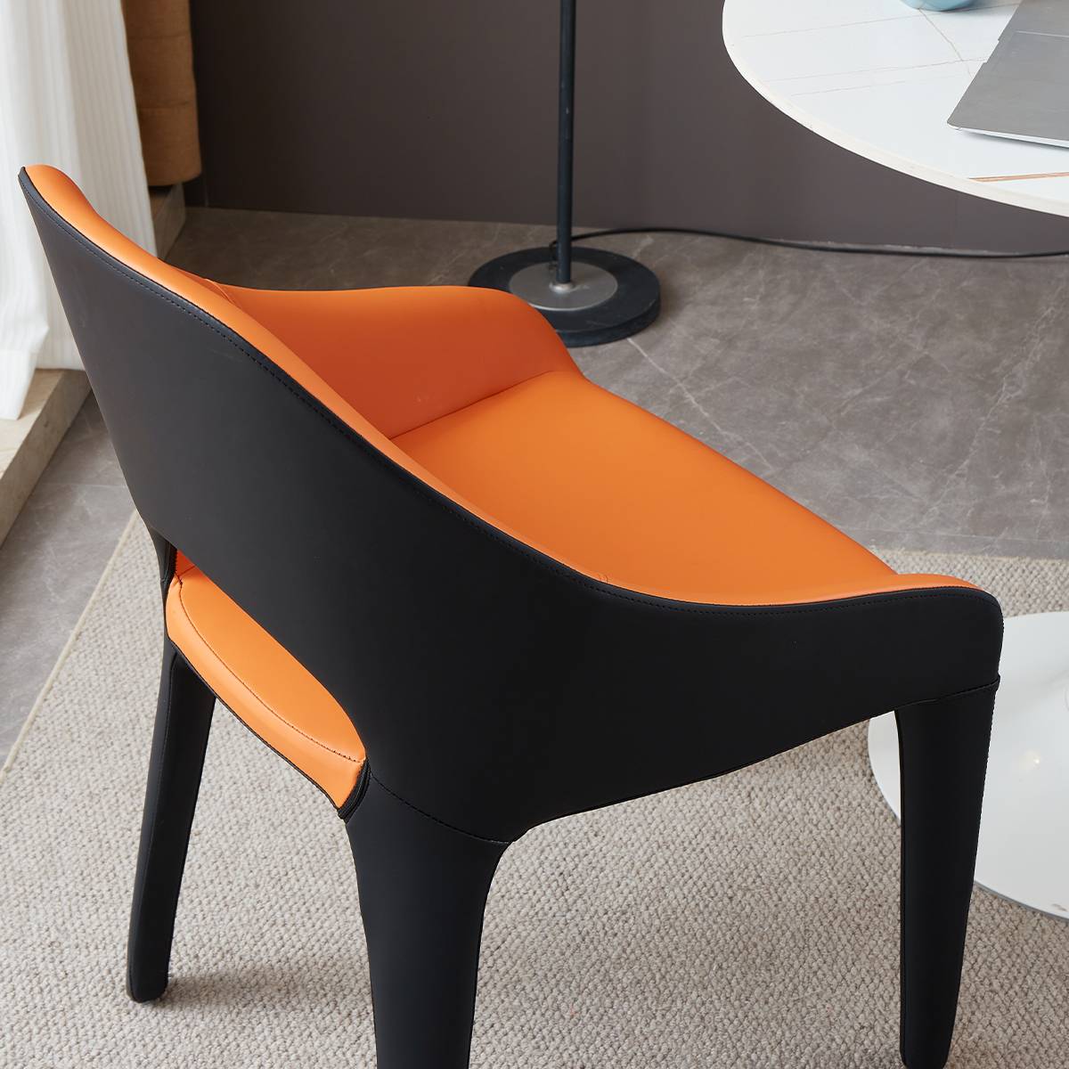 Side view of a black and orange modern lounge chair with microfiber leather upholstery
