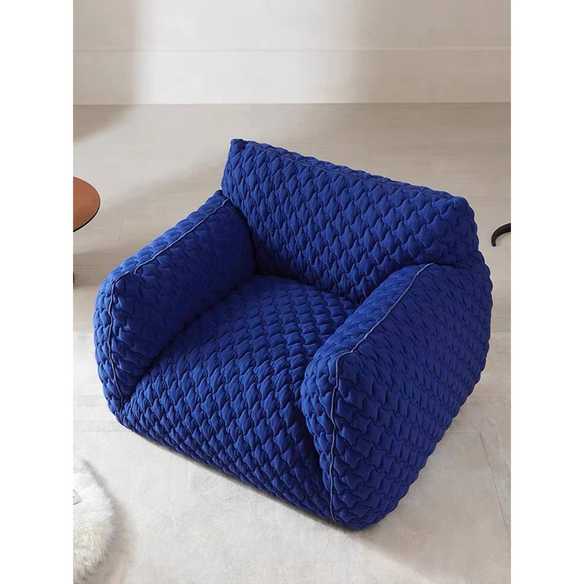Top-down view of the blue quilted lounge chair in a room setting