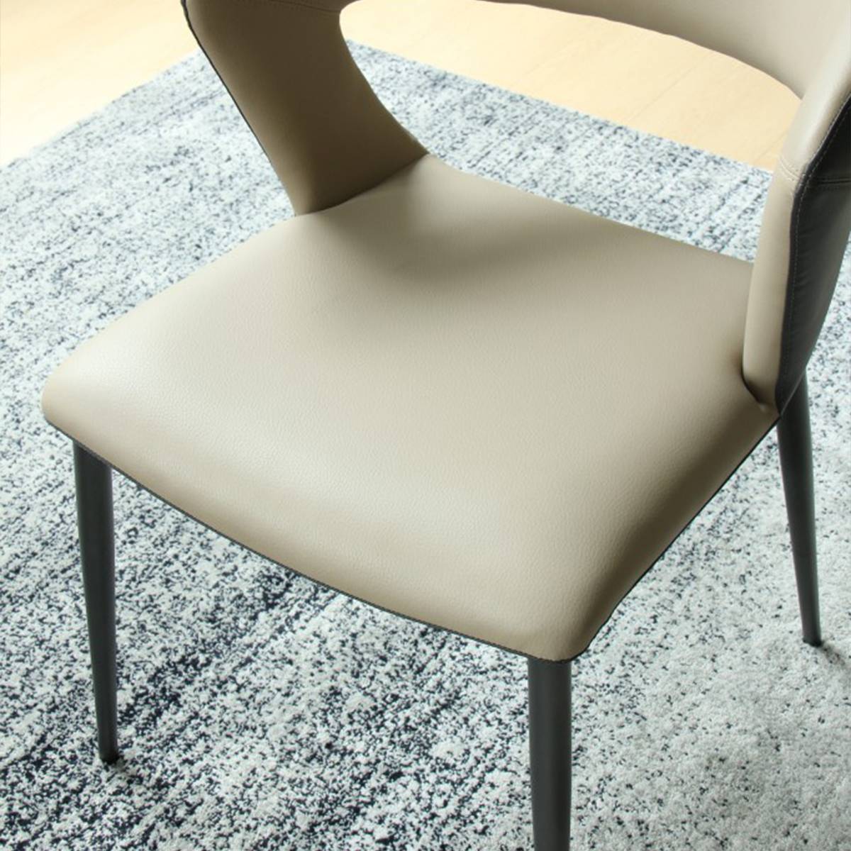 Close-up view of the beige PVC seat cushion and carbon steel legs