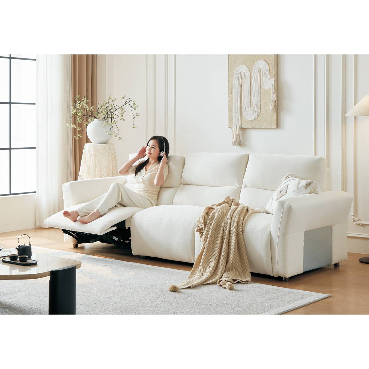 Woman relaxing on a white fabric functional sofa in a modern living room