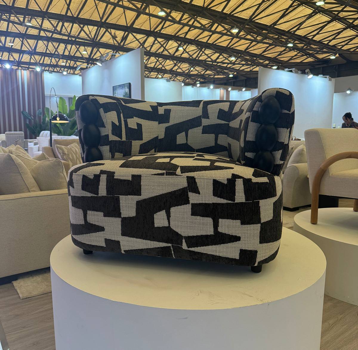Front view of the black and white geometric patterned lounge chair on a display stand