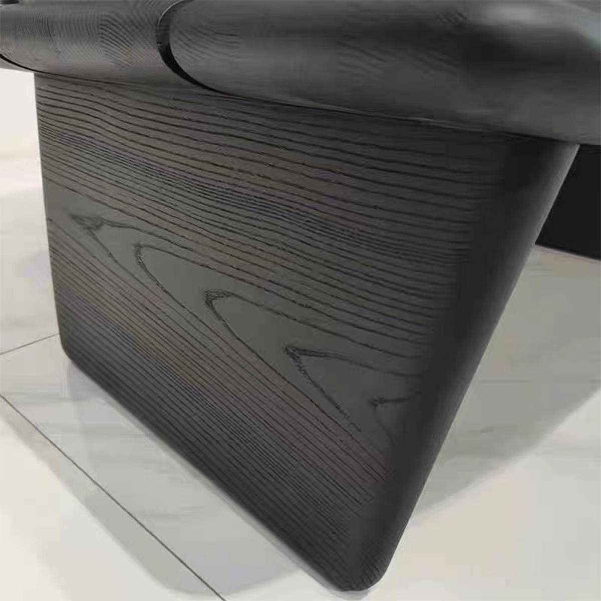 Close-up detail of the black red oak wood grain texture on the base of the lounge chair.