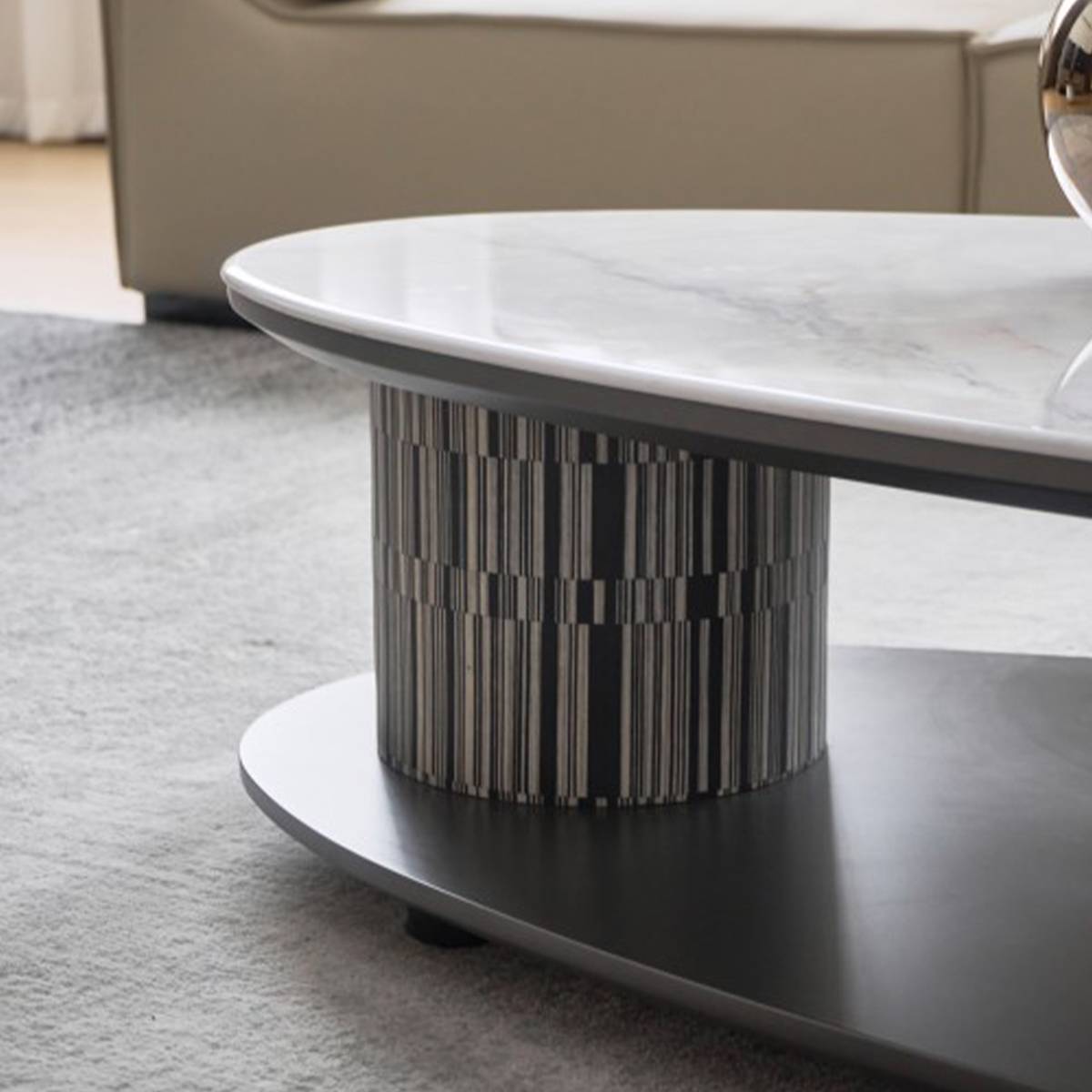 Close-up view of the coffee table's striped cylindrical base and marble top edge