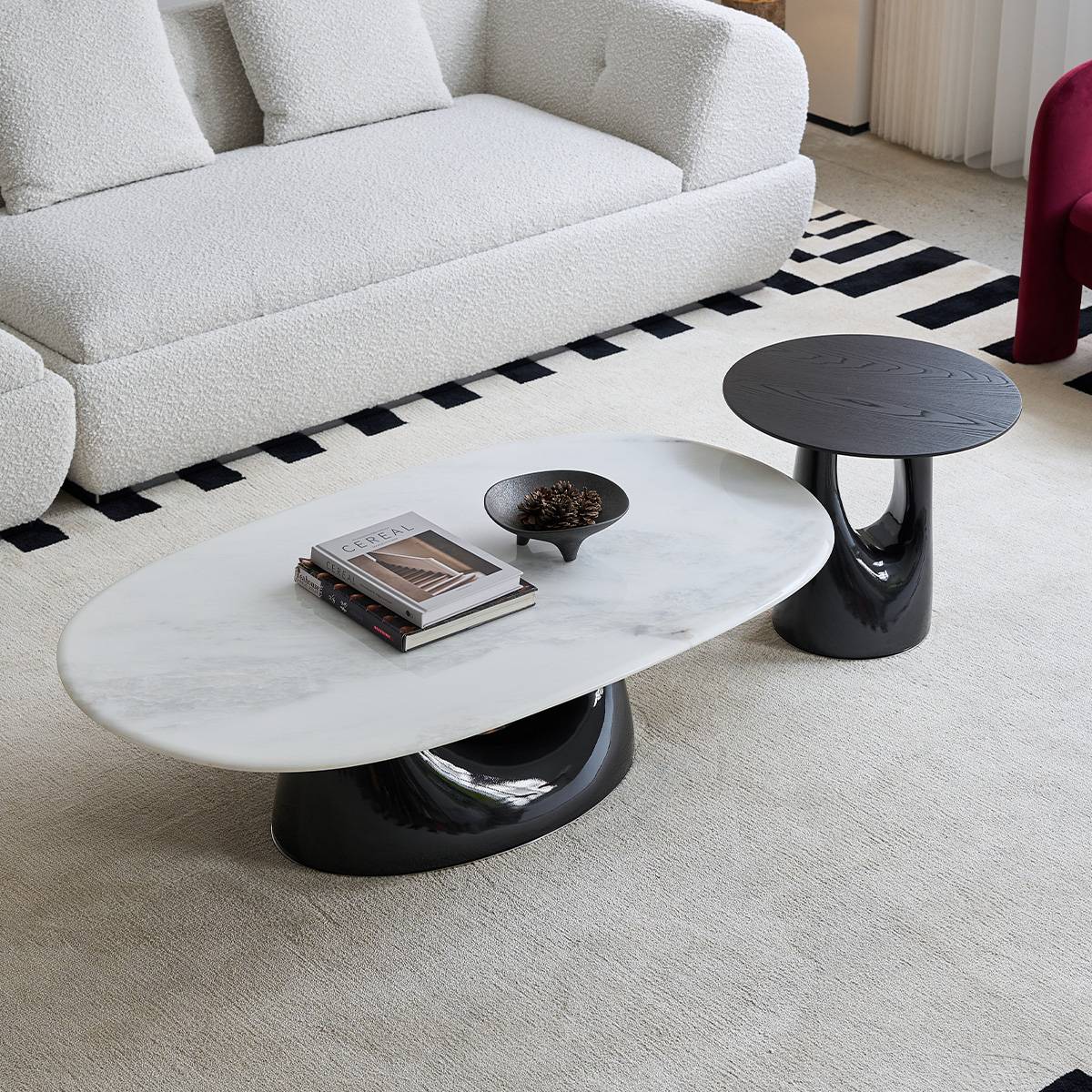 The black side table placed next to a white marble coffee table in a living room setting.