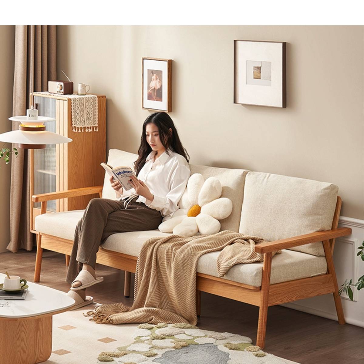 Woman reading on the sofa with beige cushions and a flower pillow