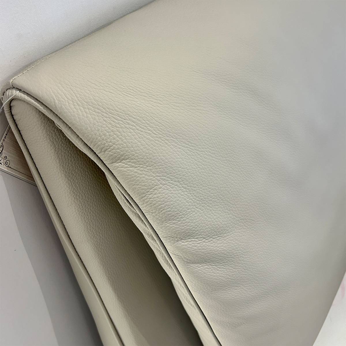 Close-up detail of the beige top-grain cowhide leather texture on the bed headboard