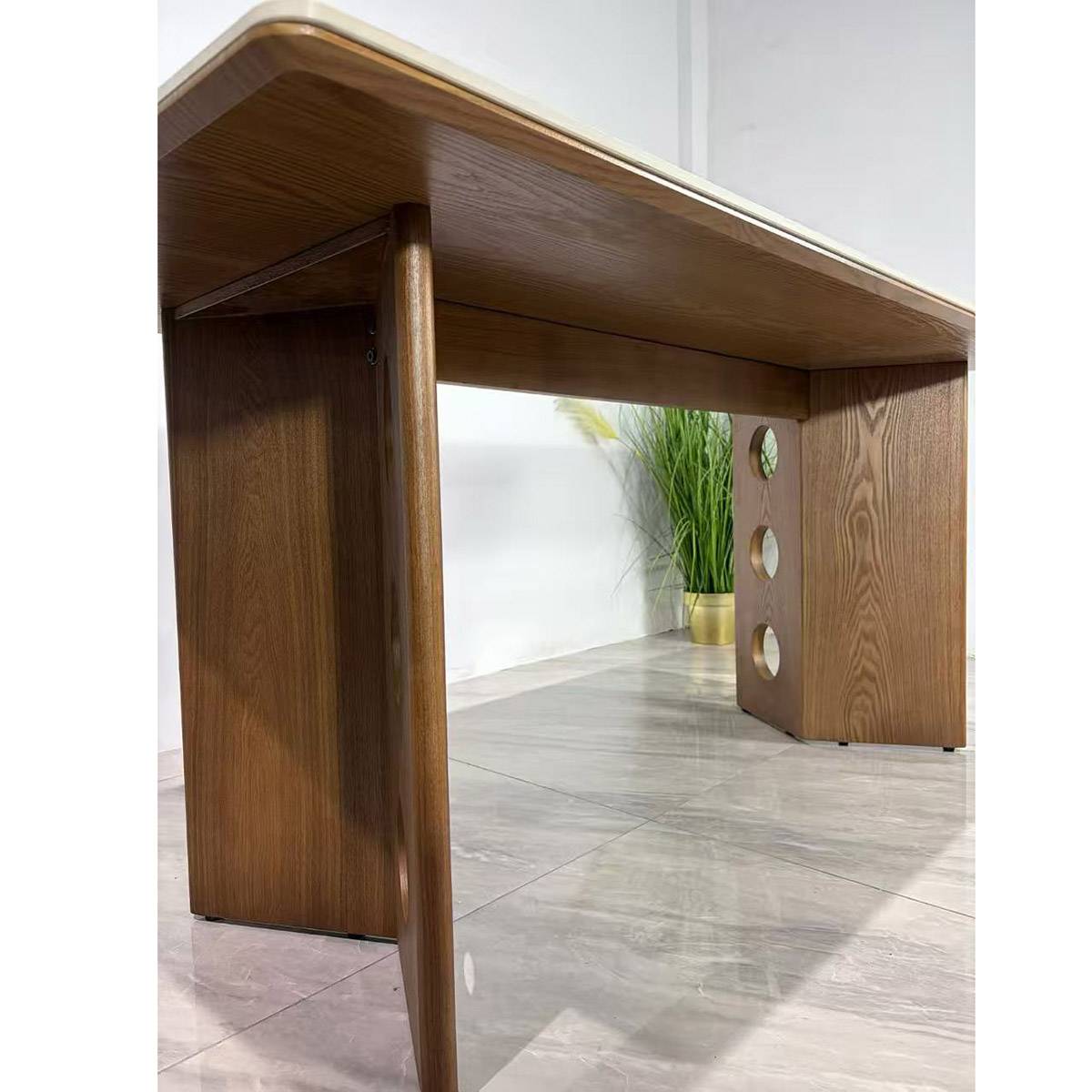 Close-up view of the dining table showing the solid walnut wood base with circular cutouts and the sintered stone top edge.